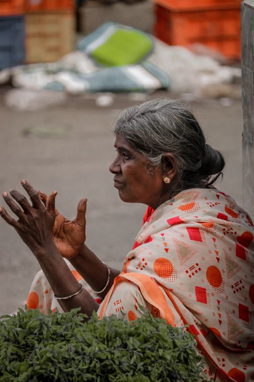 Free Portrait of an elderly woman in vibrant traditional attire, seated outdoors in Barcelona. Stock Photo