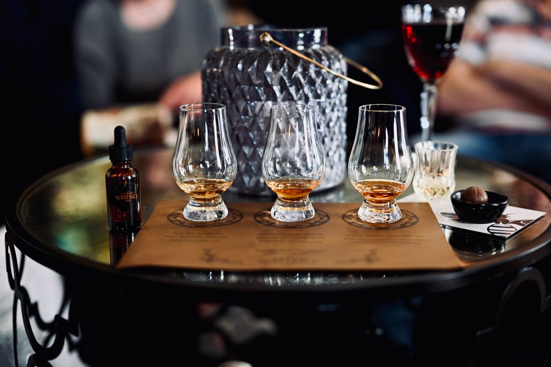 Several whiskey glasses lined up on a wooden board