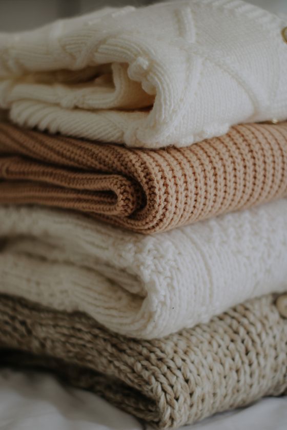 Folded knitted sweaters in warm neutral shades, photo by Nati on Pexels