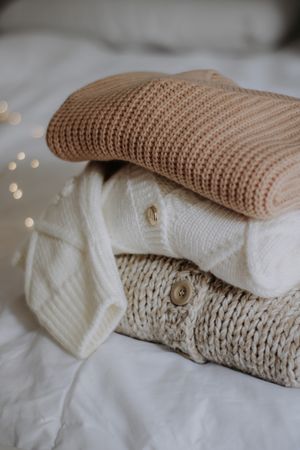 Stack of knitted jumpers in neutral tones, photo by Nati on Pexels
