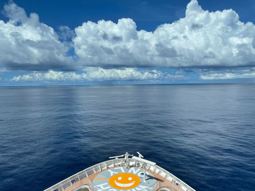 A peaceful cruise ship journey on a calm ocean under a sky filled with fluffy clouds.