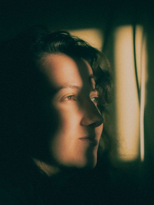Free Moody portrait of a woman with dramatic light and shadow contrast, creating an intriguing atmosphere. Stock Photo