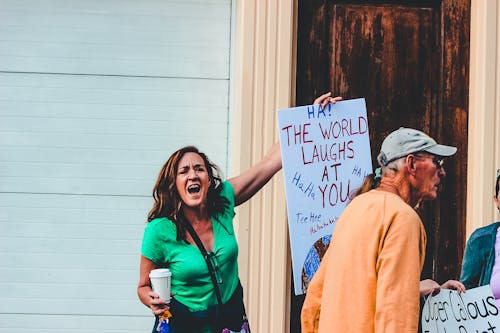 Woman Holding White Board With Ha! the World Laughs at You Handwriting