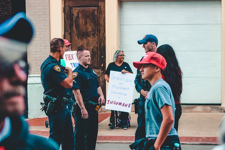 Police Standing Near Woman And Man Holding Up Signage