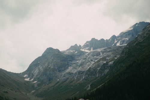 Free Majestic mountain range with snow patches under an overcast sky, perfect for scenic wallpaper. Stock Photo