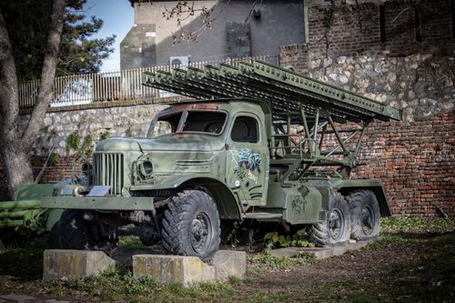 Free A vintage military truck with graffiti parked against an old brick wall. Stock Photo
