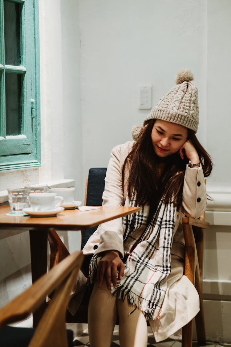 A Woman Wearing Winter Clothes Sitting On The Chair While In Deep Thought