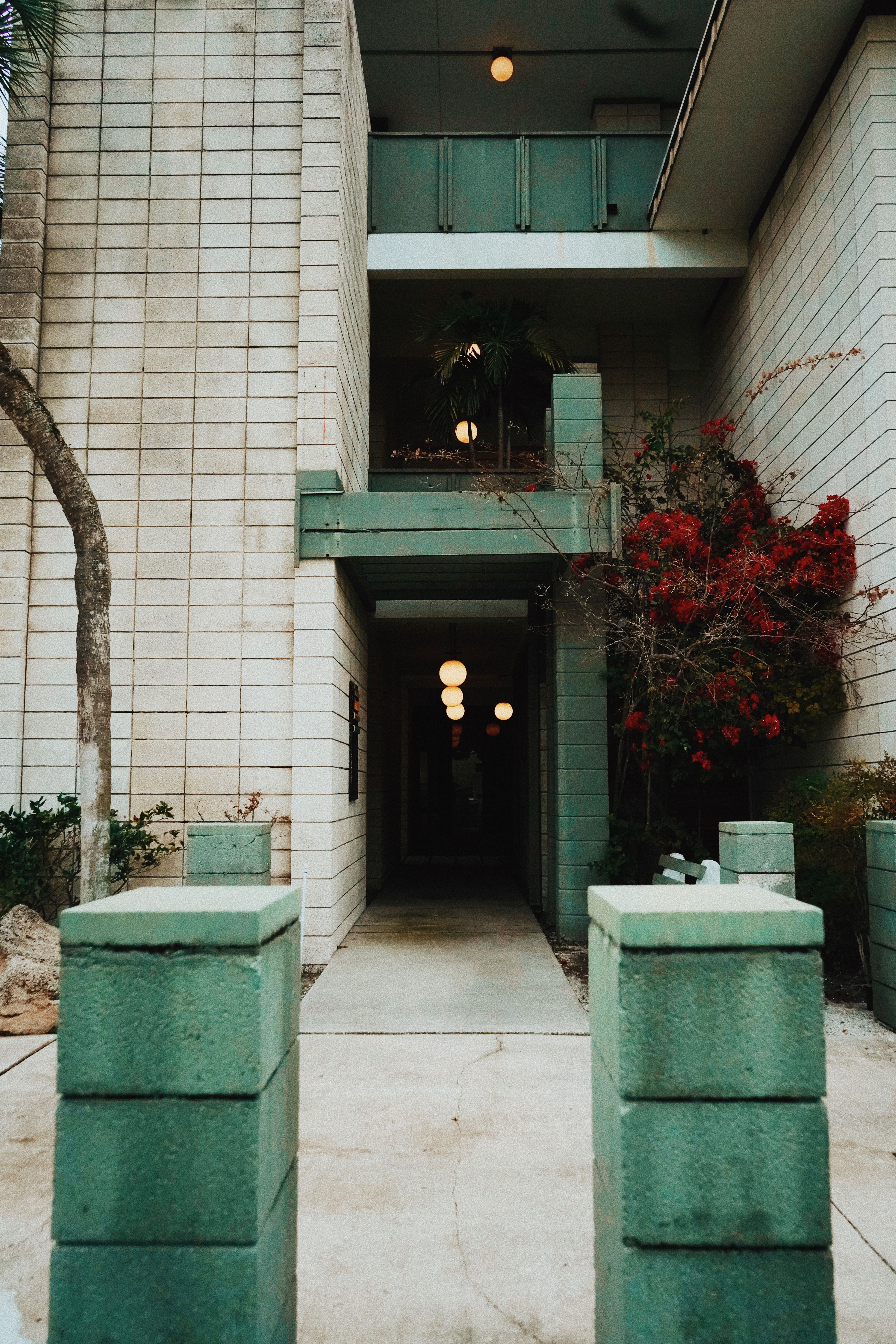A modern alley featuring a green building facade with red flowers and symmetrical architecture.