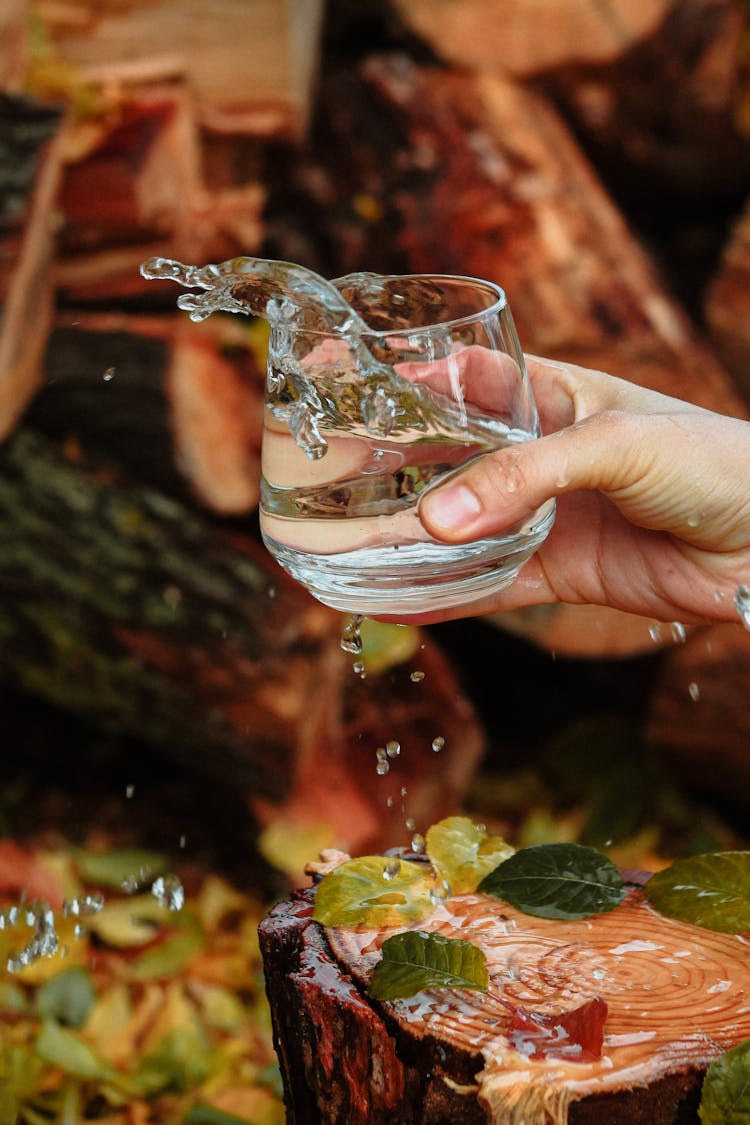 Close-up Of A Person Holding A Glass Of Splashing Water 