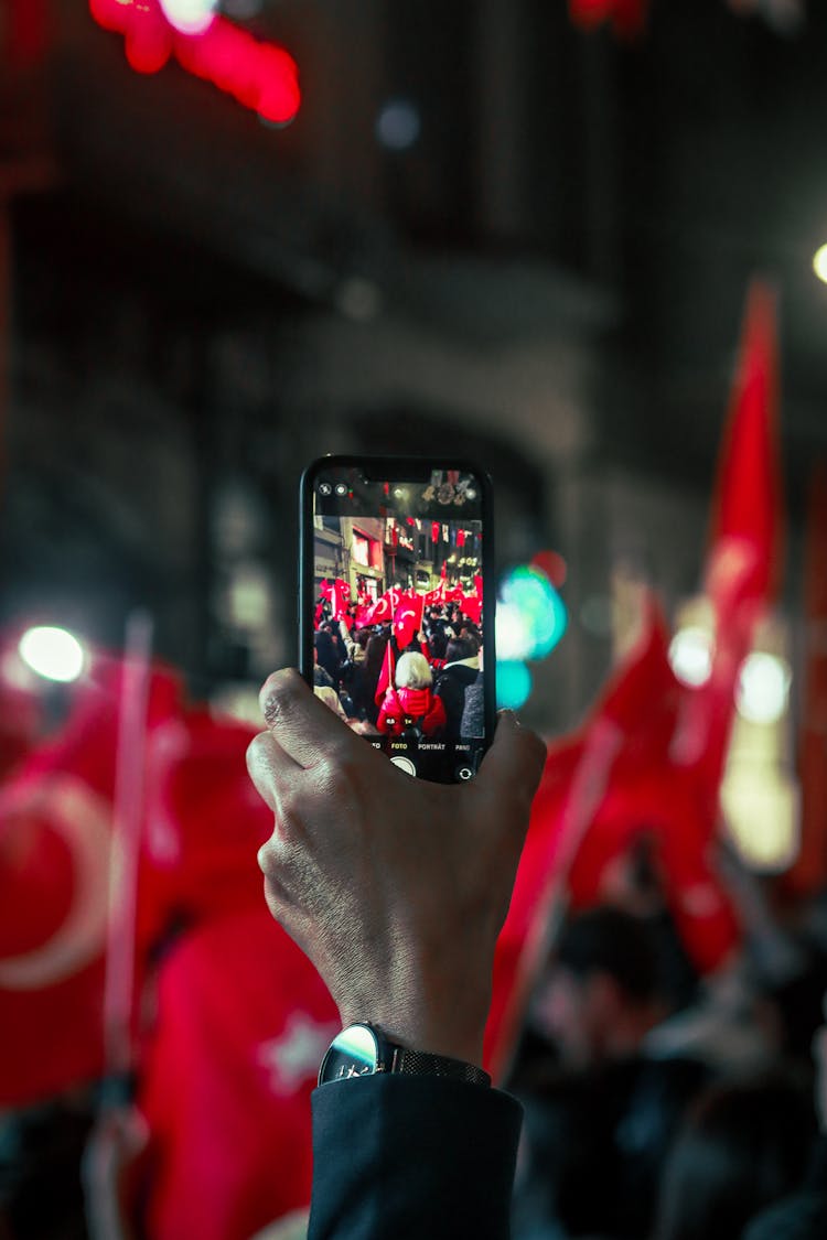 Person Taking Photo Of Parade Using Cellphone