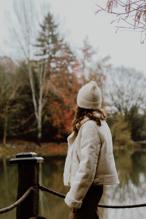 Free A Woman in White Winter Jacket and Beanie Standing on a Bridge Stock Photo