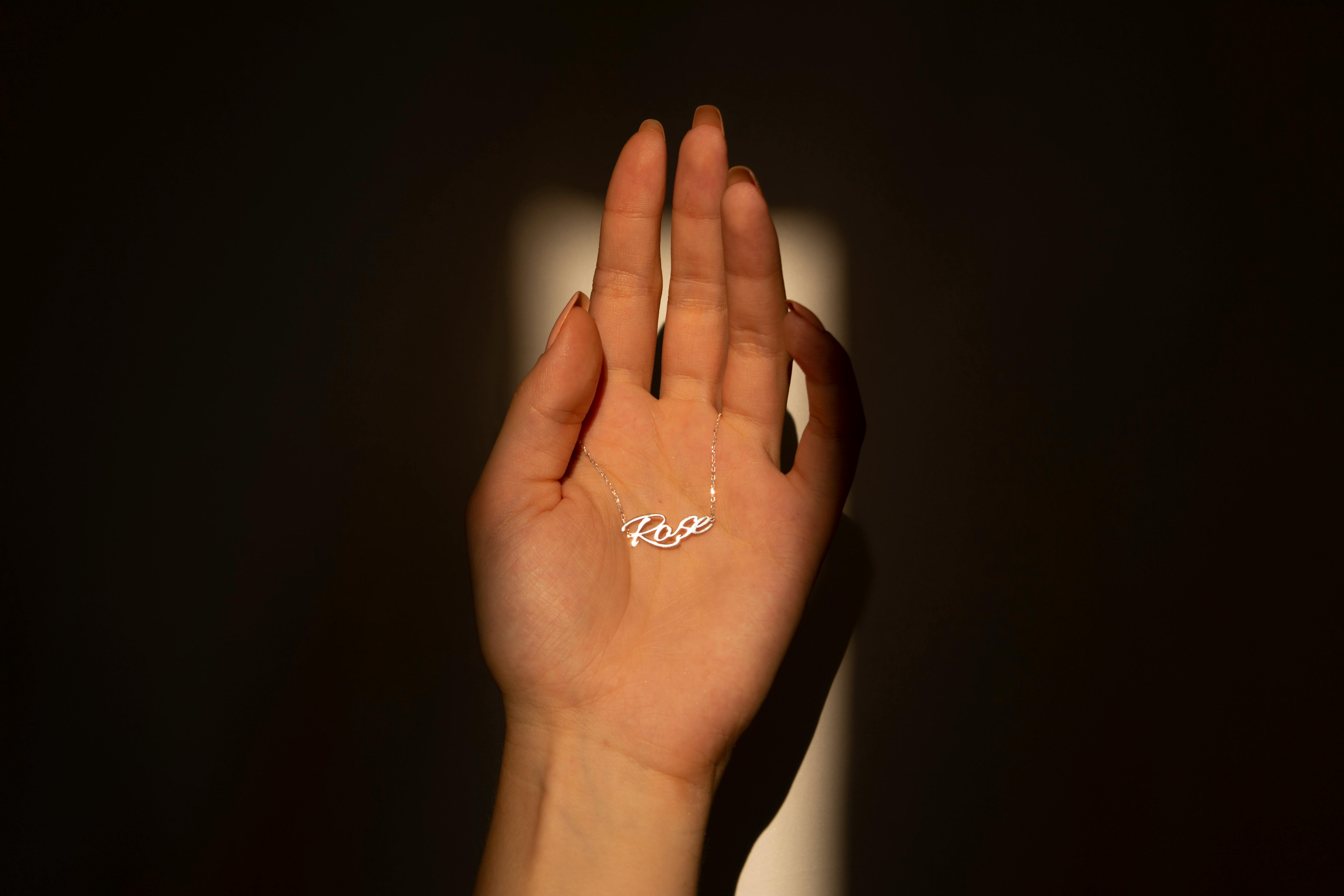 person thoughtfully holding their necklace pendant - long distance necklace for couples