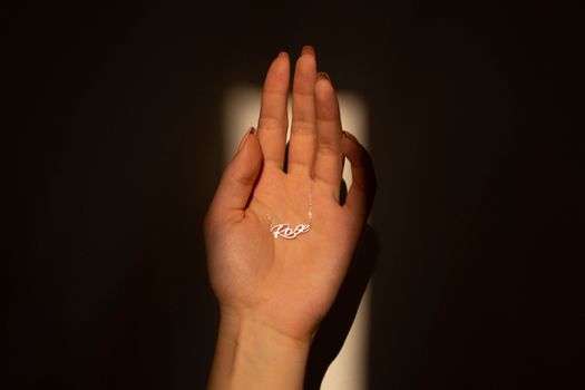 A close-up of a hand holding a delicate necklace with a 