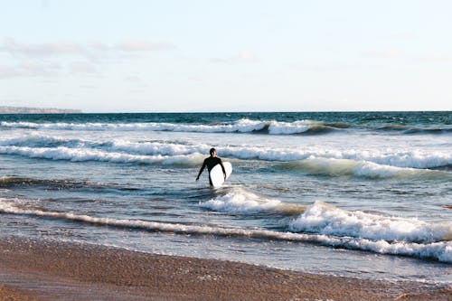 A Man Holding a Surfboard at the Beach