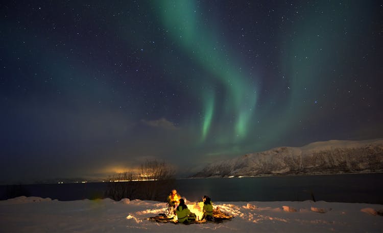 People Camping Beside A Lake Under Aurora Borealis Sky