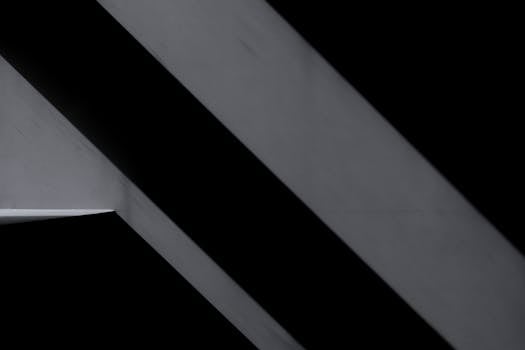 Monochrome abstract image highlighting geometric lines and shadows on a structural surface.