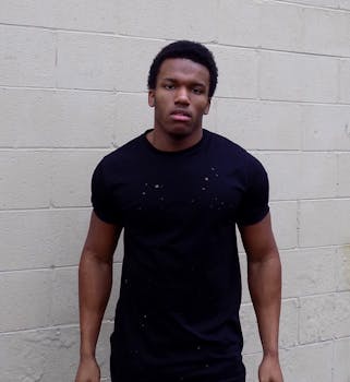 一个身穿黑色衬衫的年轻人在威廉斯堡的砖墙前摆姿势