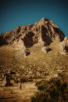 A majestic rocky mountain under a clear blue sky, captured in warm tones.