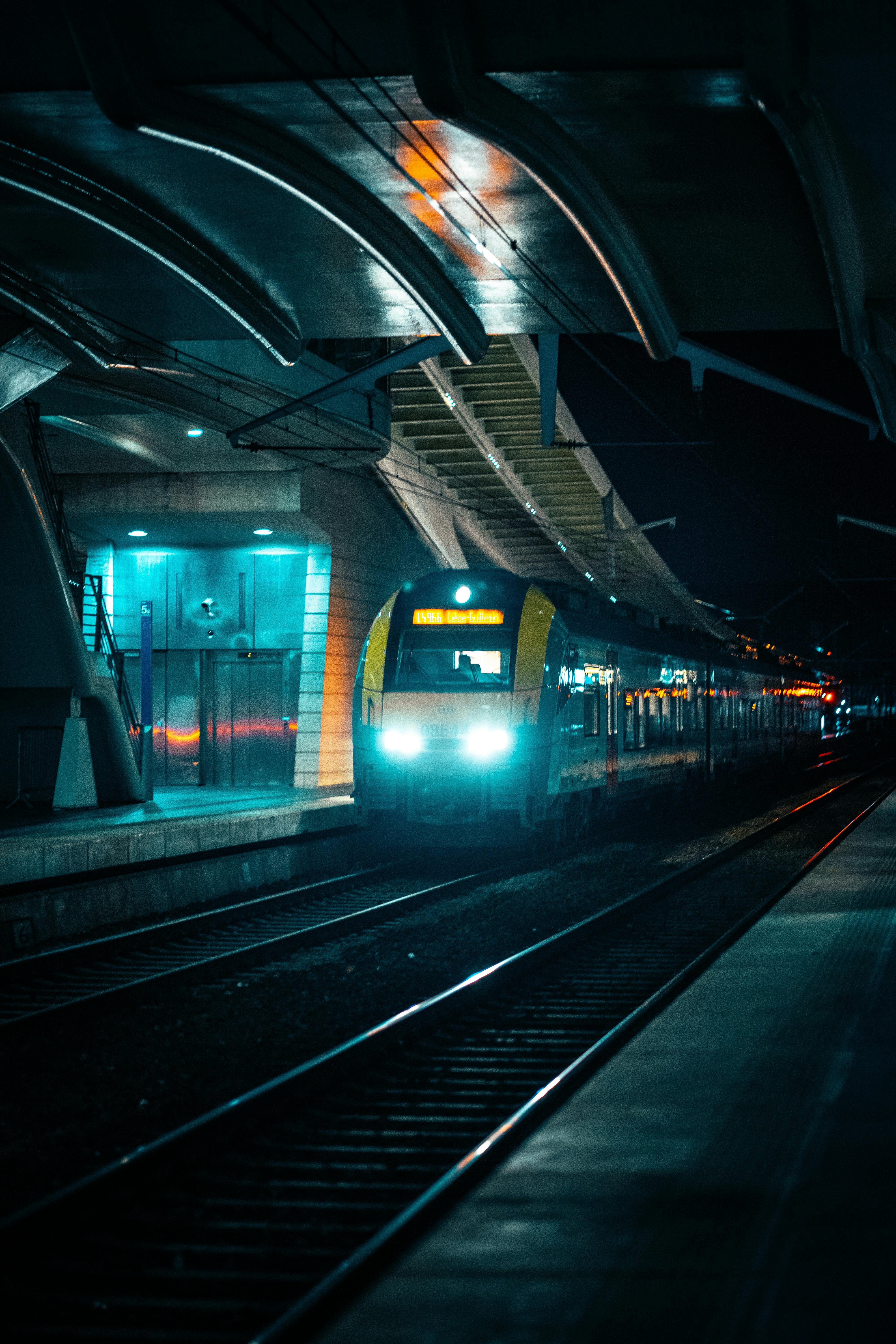 Free Illuminated train arriving at Liège station at night, showcasing modern urban transport. Stock Photo