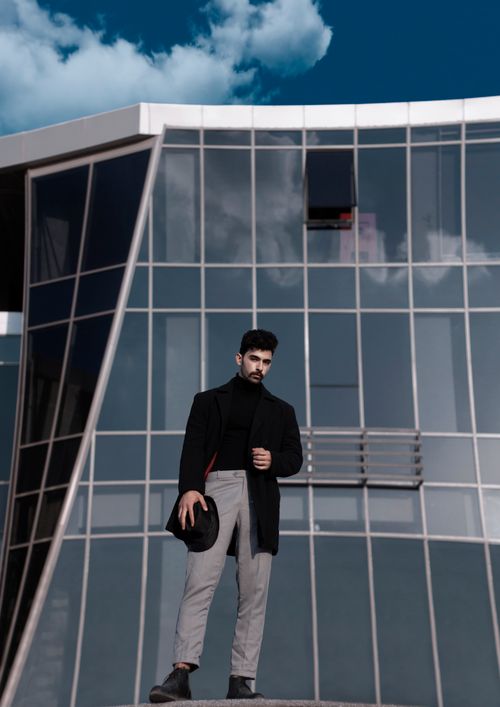 Free Stylish man poses confidently against contemporary glass architecture. Stock Photo