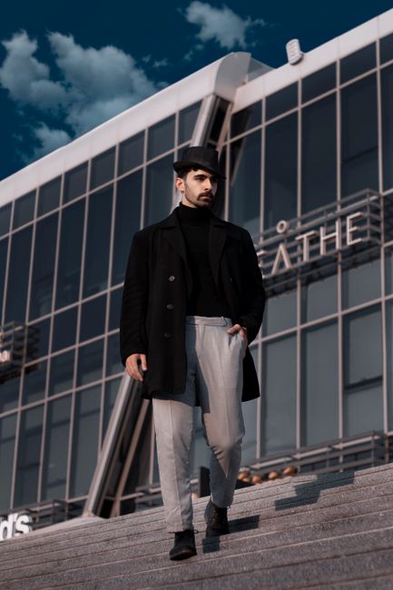 Elegant man in stylish outfit walking down stairs in front of modern building. Elegant man in stylish outfit walking down stairs in front of modern building.