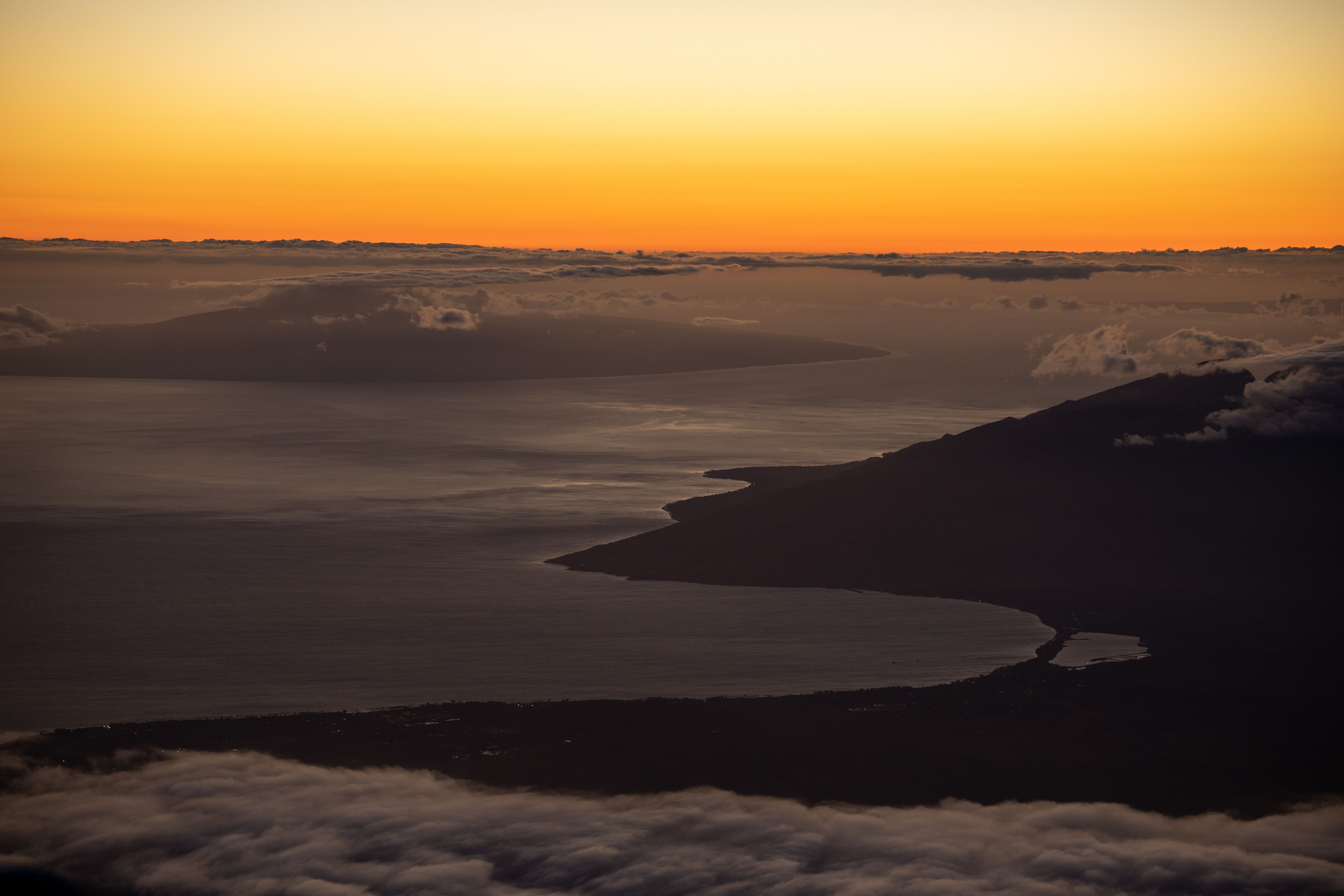 Unforgettable Hana Rainforest and Haleakala Crater Helicopter Tour Review: Your Complete Guide to Maui's Most Scenic Flight Review 2026 - Stunning aerial view of a sunset over the ocean with a dramatic coastline and soft clouds.