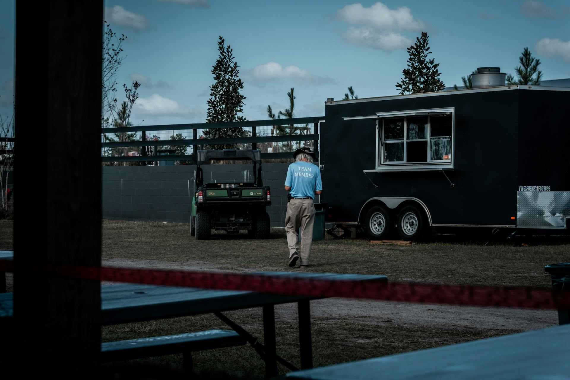 Photo of a Man in a Light Blue T-Shirt Approaching a Black Trailer