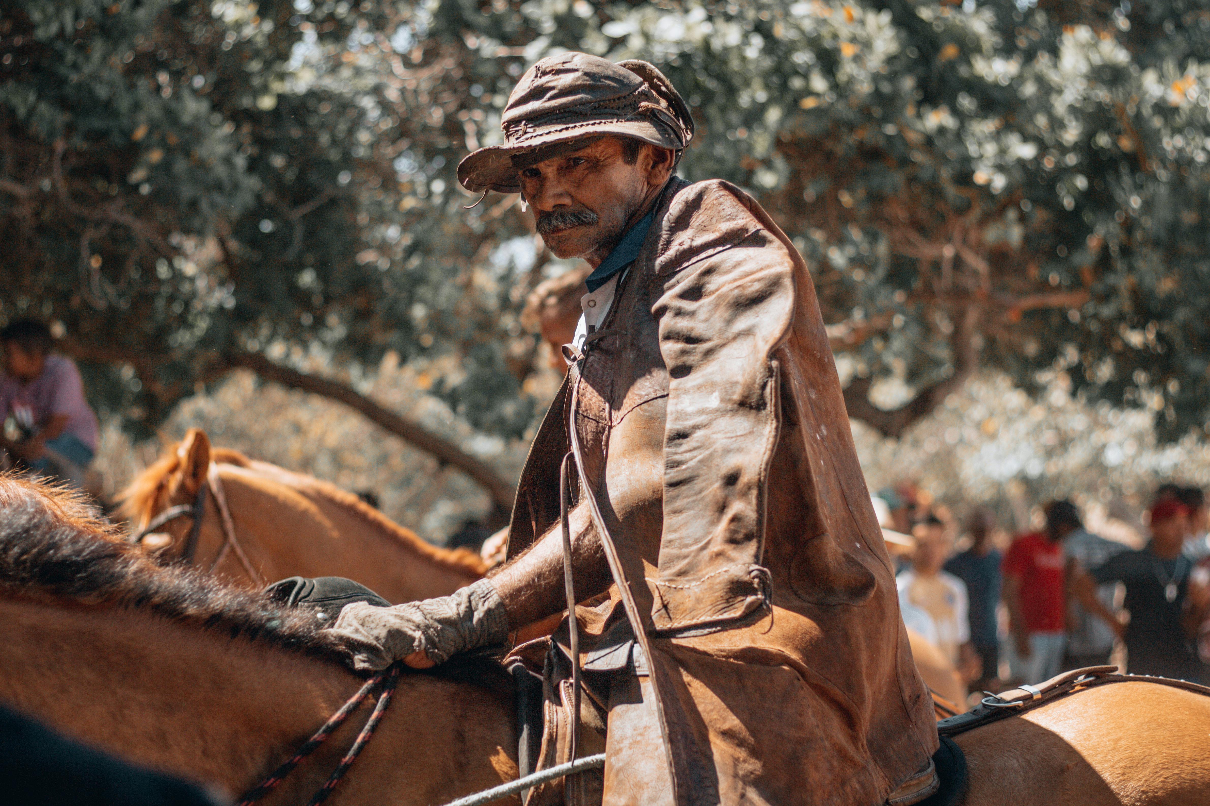 Elderly man in a brown leather jacket riding a horse in Aracati, Brazil.