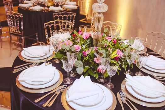 Luxurious dining table setup with elegant floral centerpiece and fine tableware for a formal banquet setting.