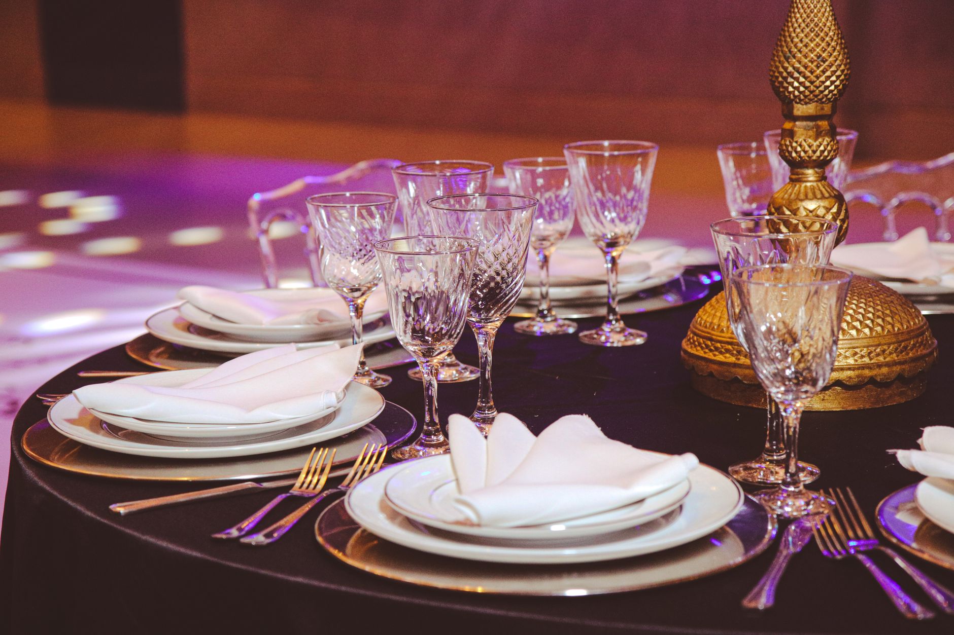 A luxurious dining table setup featuring crystal glasses, elegant plates, and golden decor for a sophisticated ambiance.