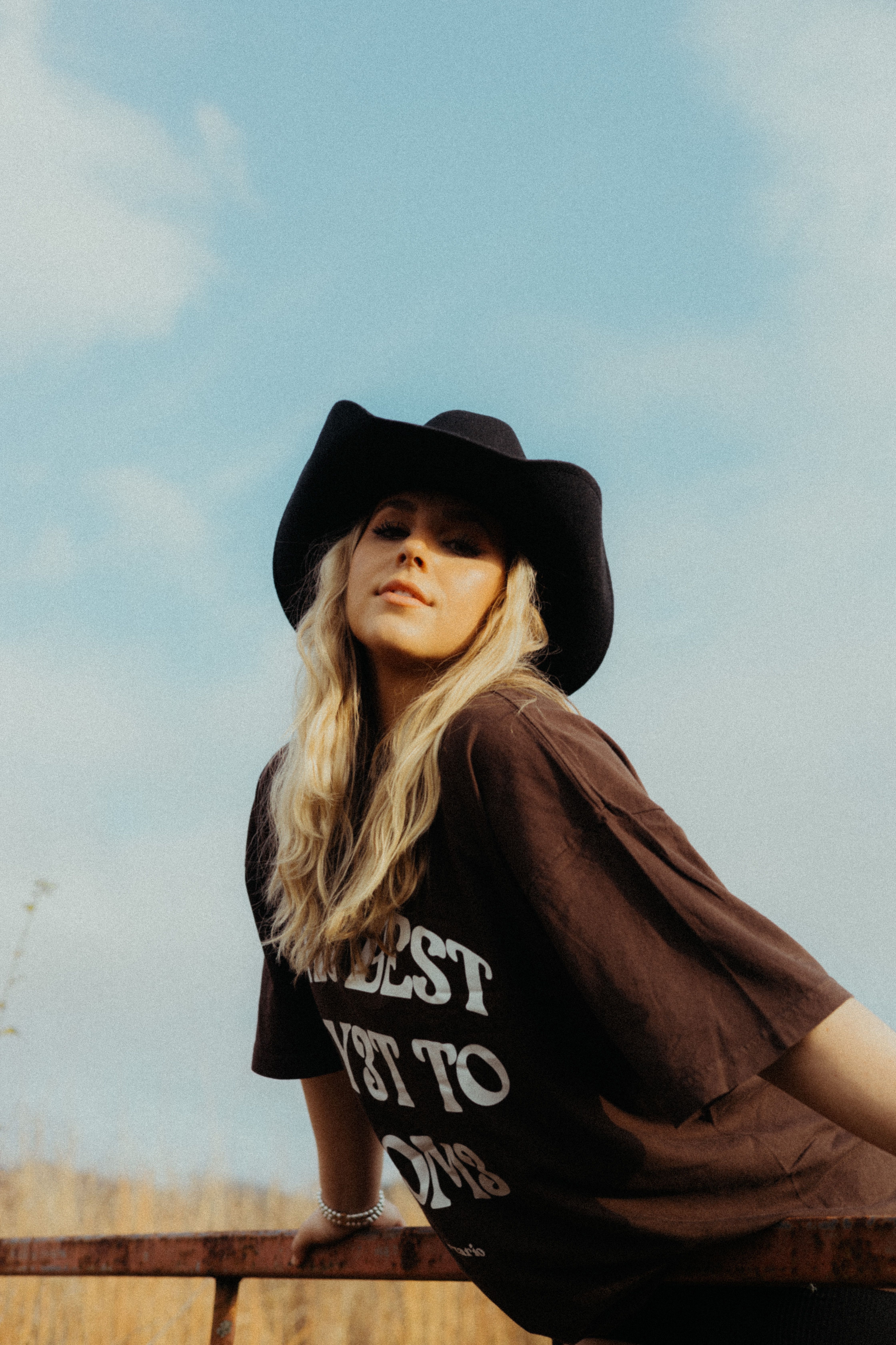A woman wearing a cowboy hat and casual t-shirt poses outdoors in Tennessee.