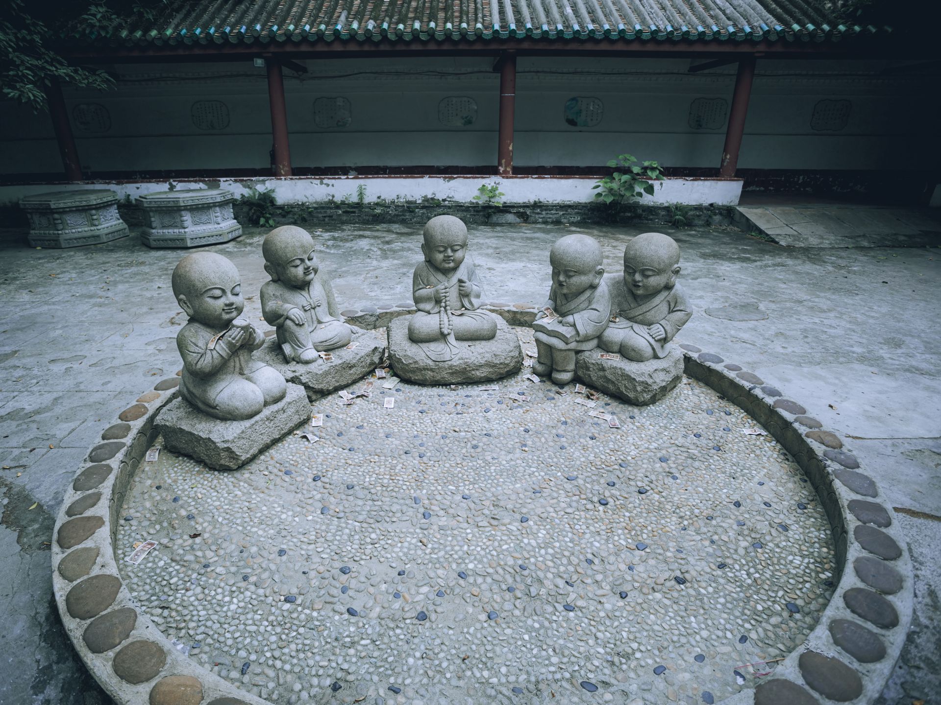 Five stone monk statues sit serenely in an outdoor courtyard, exuding tranquility and spiritual calm.