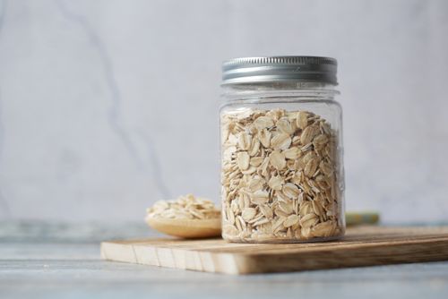Free A jar filled with oats sits on a wooden cutting board, showcasing a minimalist kitchen decor. Stock Photo