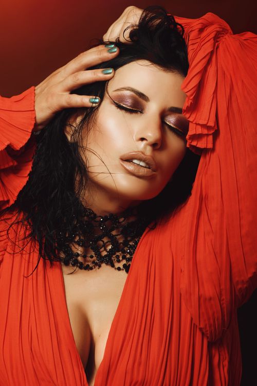 Free Portrait of an elegant woman in a red dress with dramatic eye makeup and closed eyes, exuding glamour and sophistication. Stock Photo