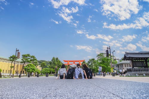 Four Girl's Sitting on Gray Concrete Floor Under Blue Sky