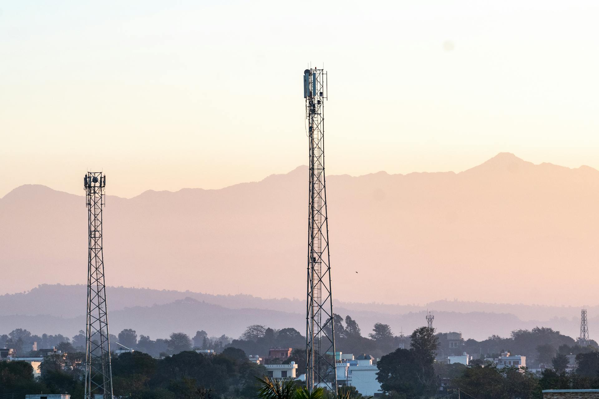 Cell Towers Surrounded with Houses and Trees Near the Mountains