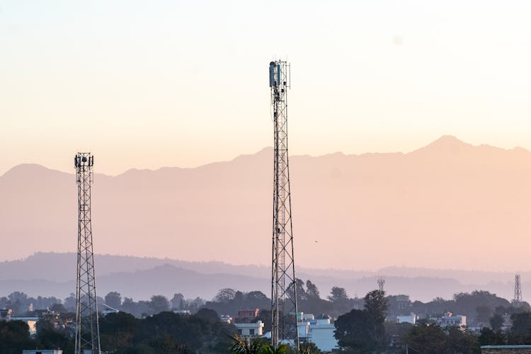 Cell Towers Surrounded With Houses And Trees Near The Mountains