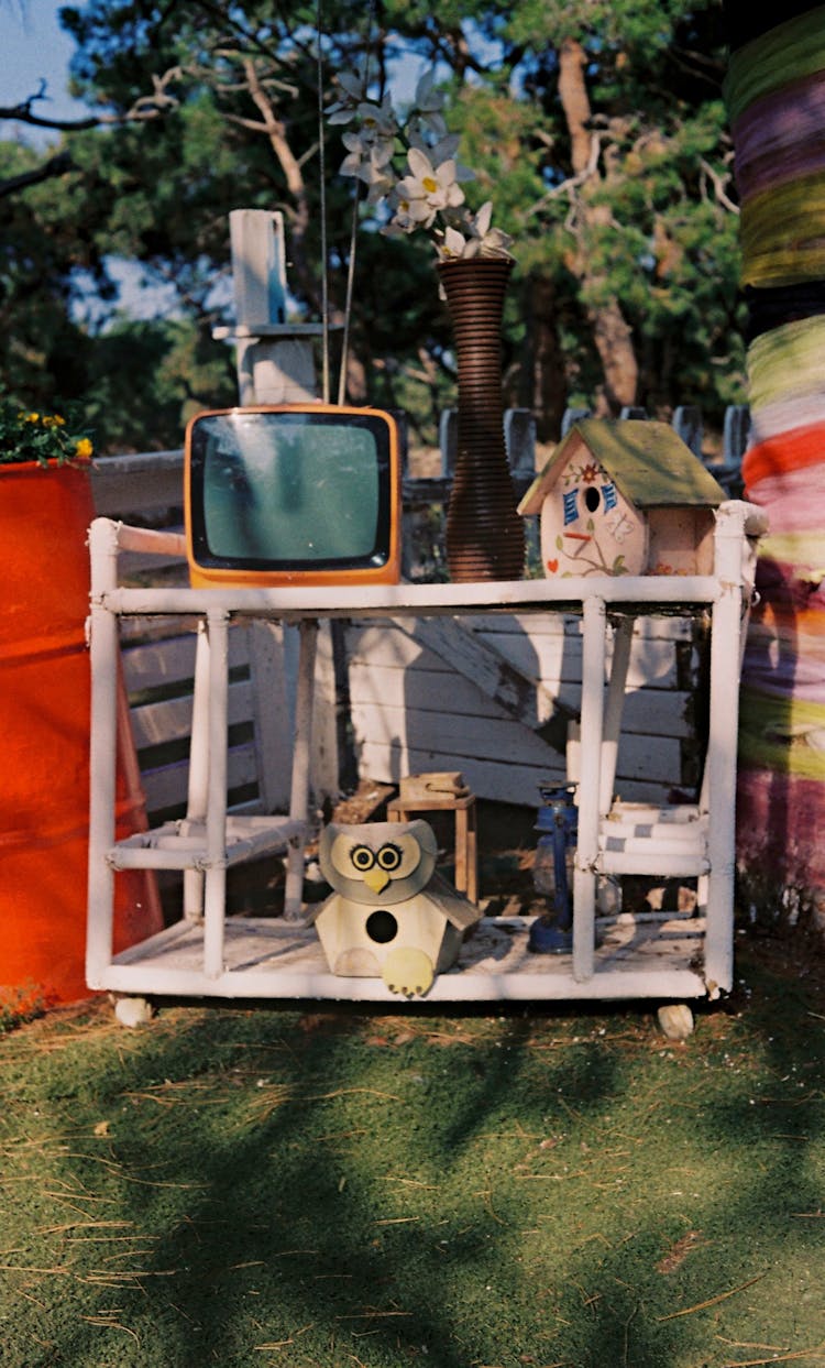 Small TV And Handmade Decorations Standing On A Shelf Outside 