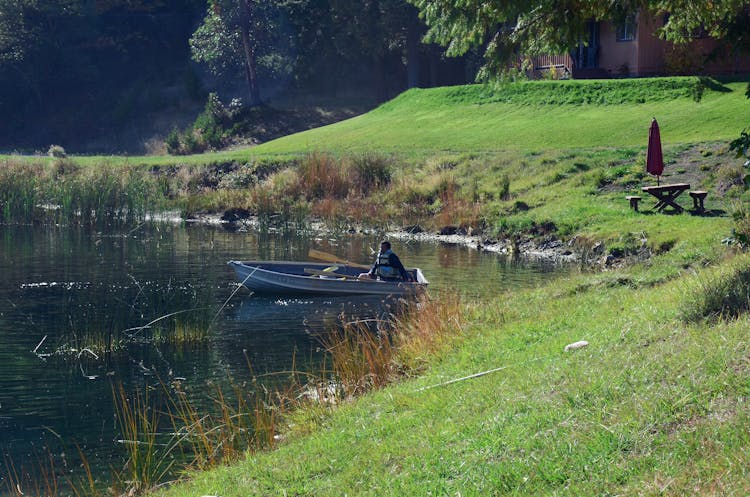 A Man Sailing A Boat On A Lake