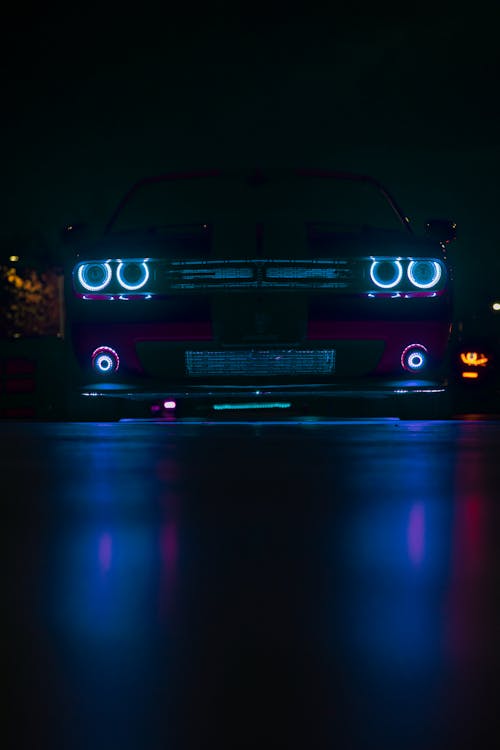  Dodge Challenger with Blue Headlights Reflecting in the Street Surface at Night 