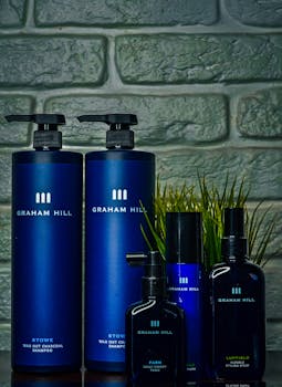 Graham Hill cosmetic bottles on display against a textured brick wall.