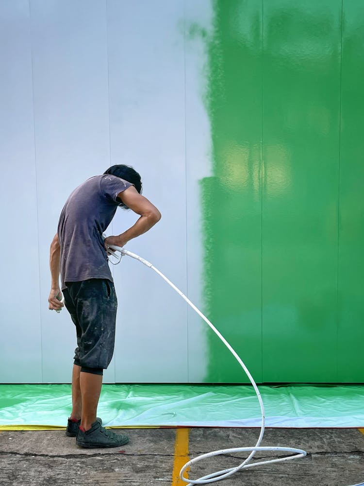 Man Painting A Wall White With A Paint Sprayer 