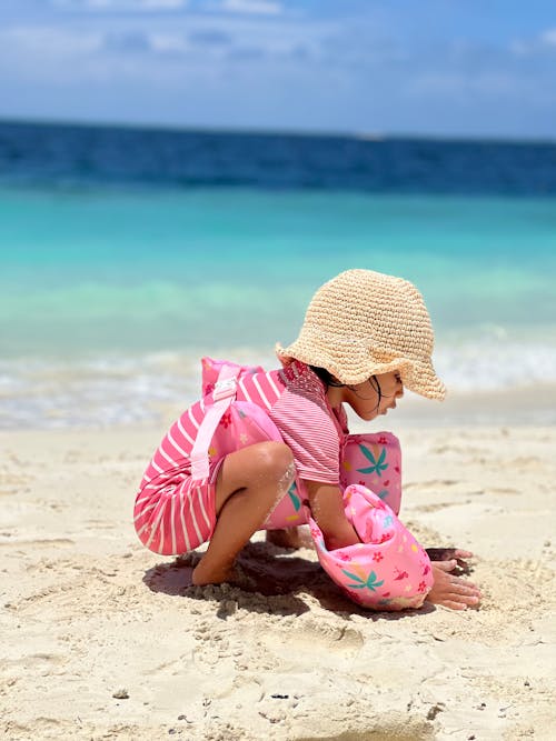 Free Little Girl Playing with Sand on a Beach  Stock Photo