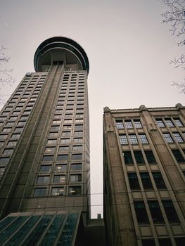 A low-angle view of a modern skyscraper beside a historic building in Vancouver, Canada.