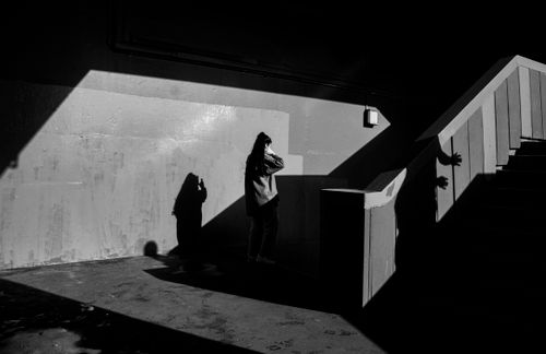 Free Dramatic black and white silhouette of a woman standing near a shadowed wall and staircase. Stock Photo