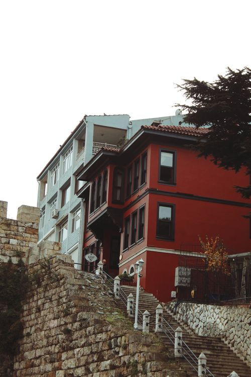 Free Charming townhouses with red and blue facades viewed from below. Stone steps and railings add rustic charm. Stock Photo