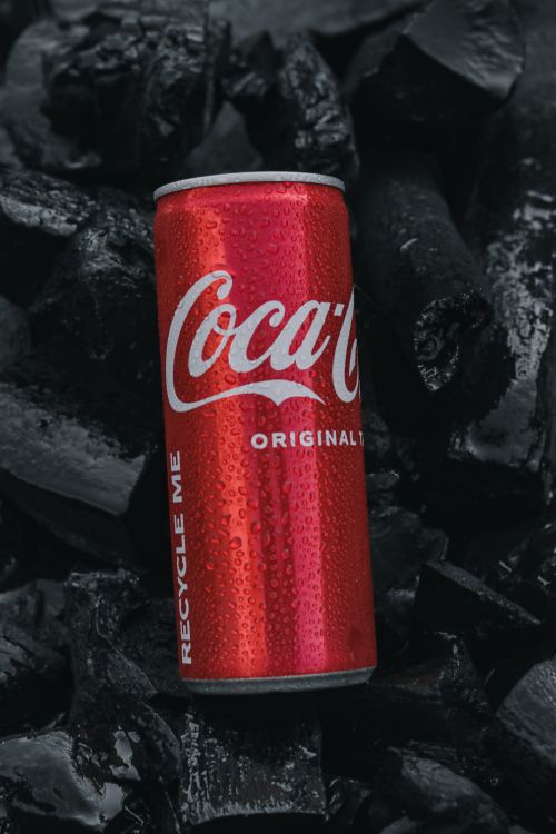 Free A cold Coca-Cola can with droplets on a dark textured background, highlighting the brand's iconic design. Stock Photo