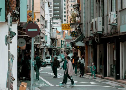 Free Busy city street with pedestrians crossing among tall buildings in daylight. Stock Photo