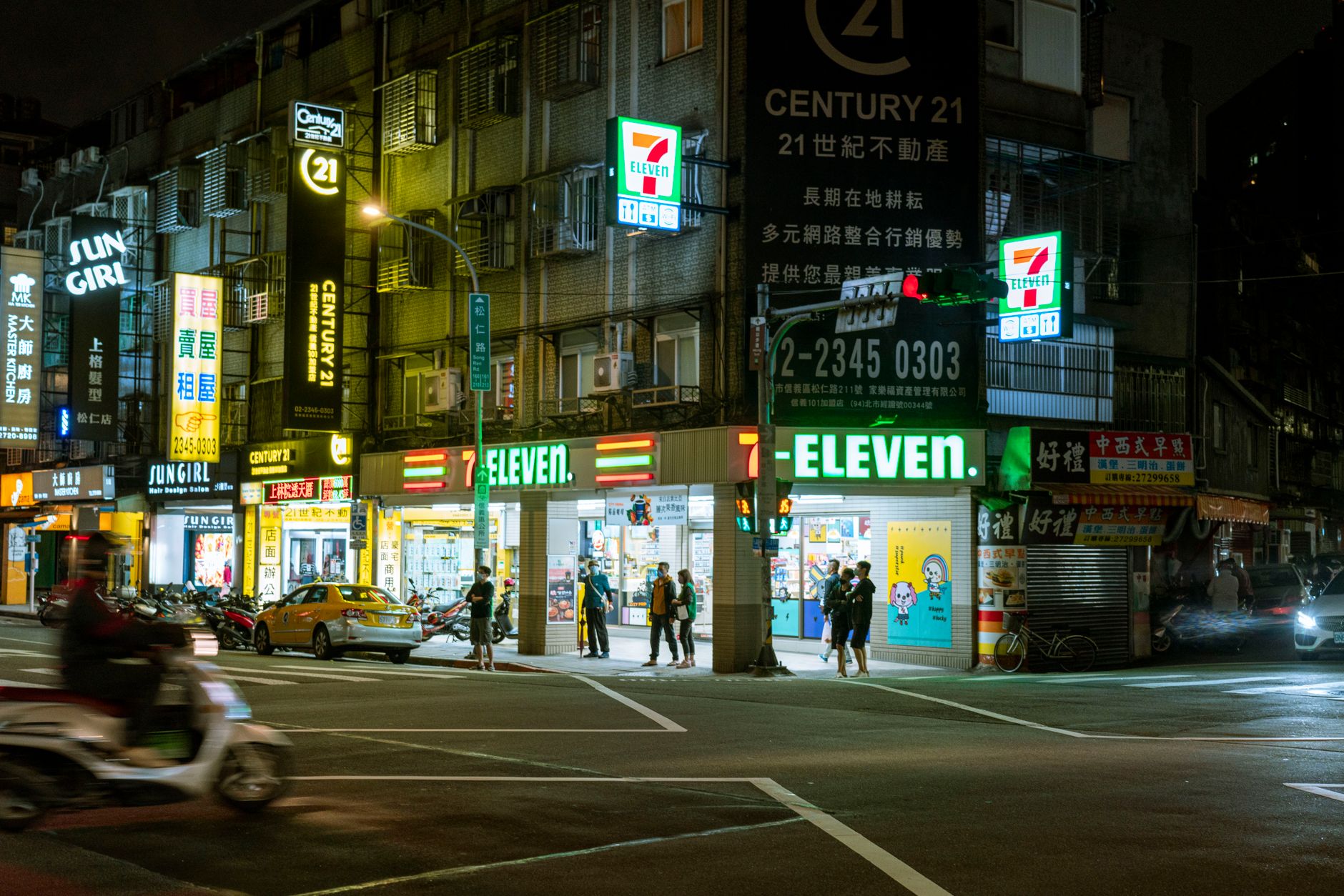 Night view of a bustling 7-Eleven store with vibrant city lights and street activity.