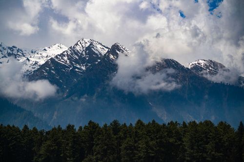 Free Breathtaking view of snow-capped mountains and lush forests under cloudy skies in Jammu, India. Stock Photo
